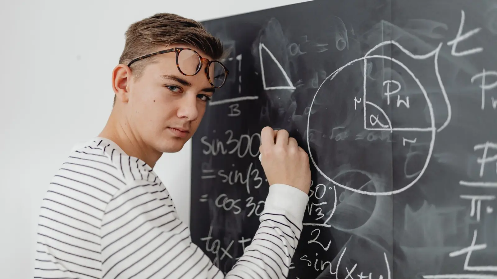 A student working through geometry and trigonometry equations on a blackboard, one of the maths topics examined in the Abitur