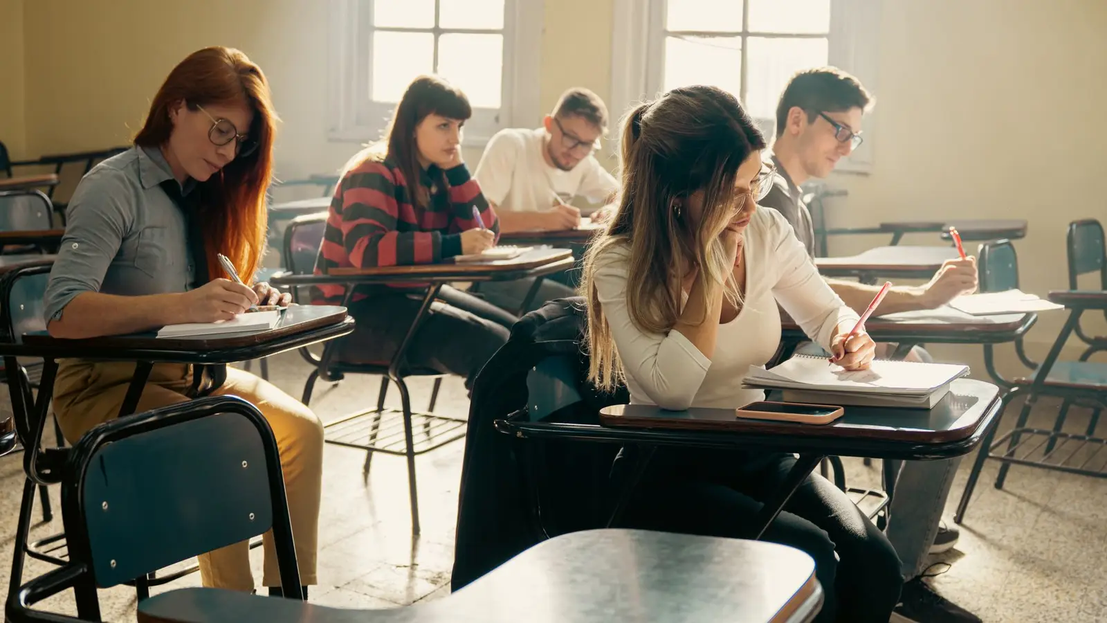 Étudiants post-bac composant une épreuve écrite sur des tables individuelles, le format des concours des grandes écoles