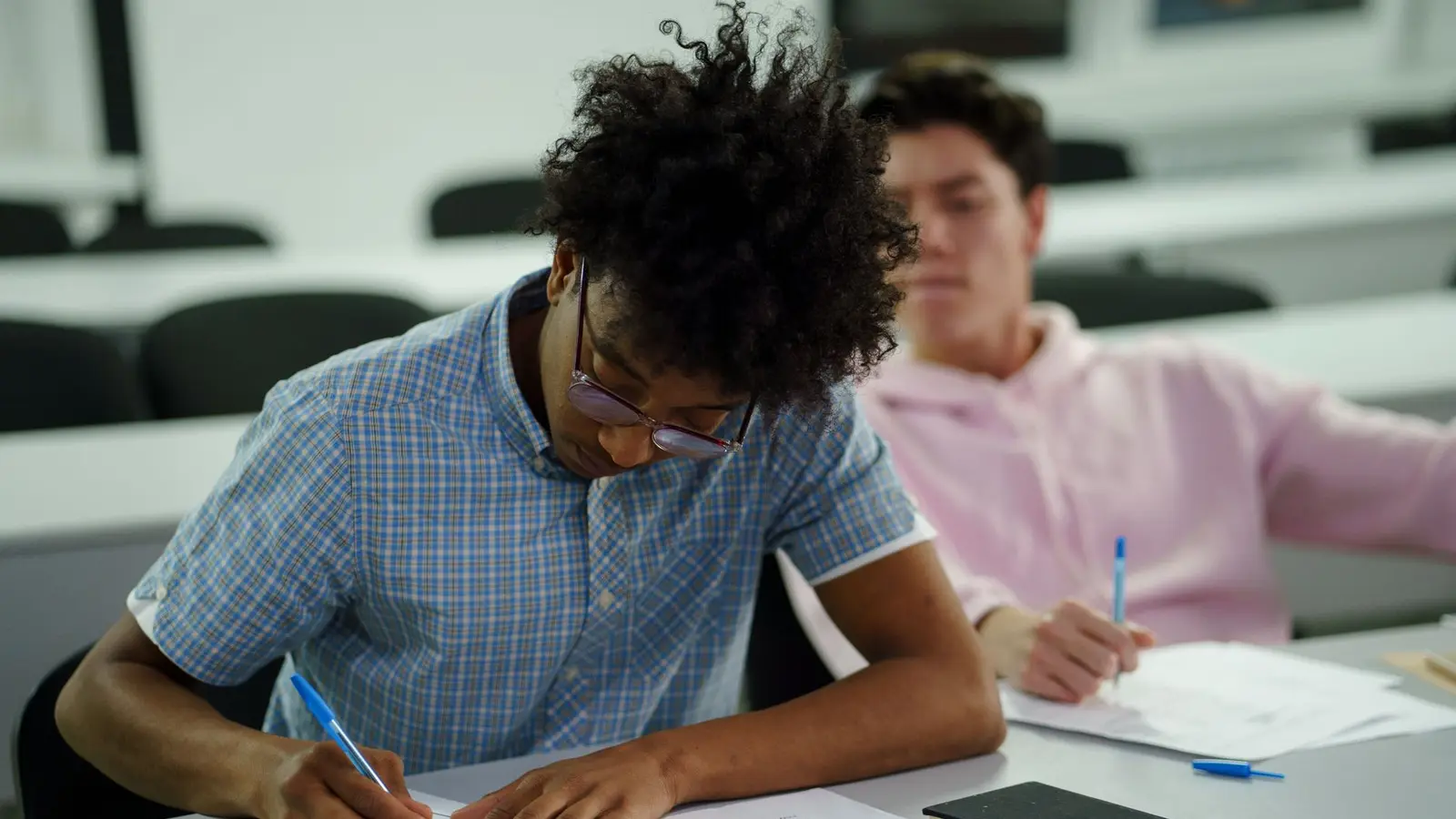 Two secondary school students writing a final written exam at classroom desks, the exam format used for the German Realschulabschluss