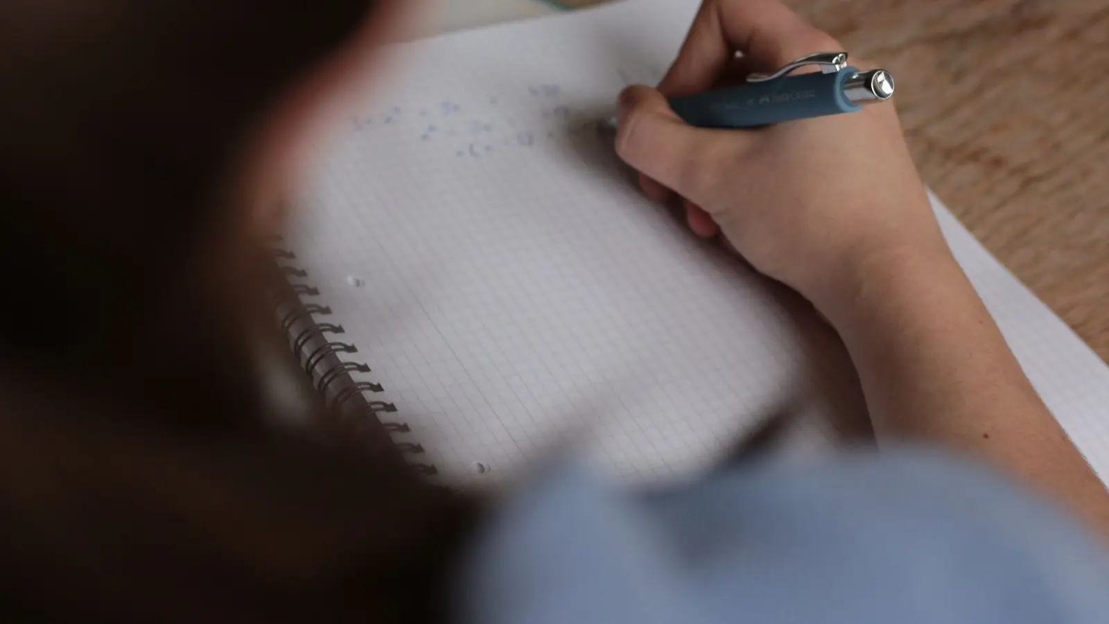 A student revising maths in a squared notebook while preparing for the French brevet and bac exams in June.